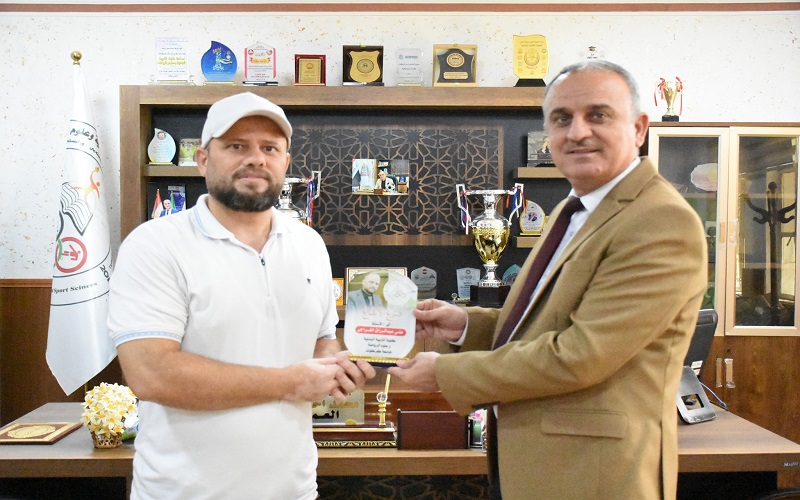 عميد كلية التربية البدنية وعلوم الرياضة يقدم درع التميز والابداع لمسؤول شعبة الاعلام والاتصال الحكومي 